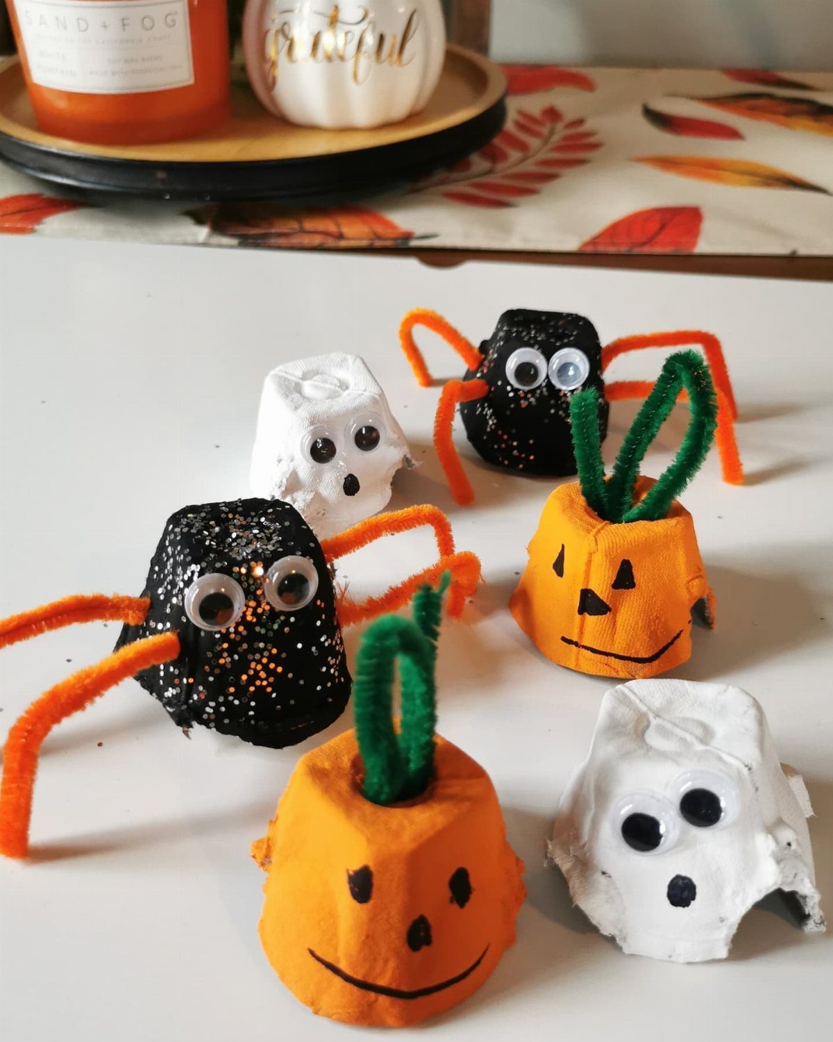 Egg carton Halloween crafts including orange pumpkins, black spiders, and white ghosts.
