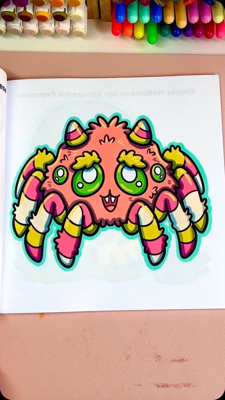Colored cute spider drawing inside an open coloring book with markers above it