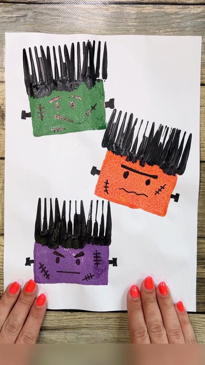 Three colorful painted monsters with black fork-painted hair on a white piece of paper.