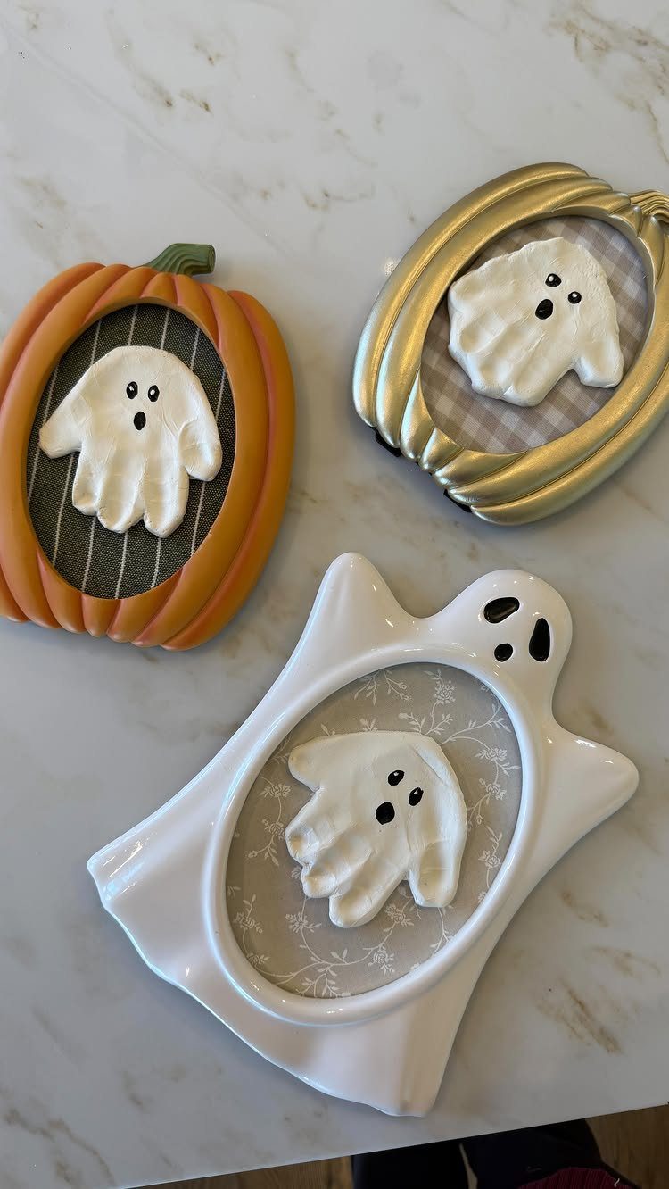 Three white ghost handprints displayed inside pumpkin and ghost shaped decorative frames.