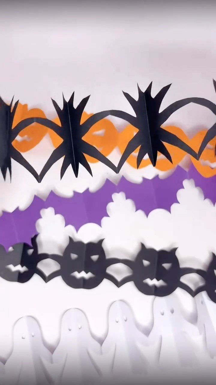 Paper garlands with black spiders, white ghosts, and black bats for Halloween decorations.