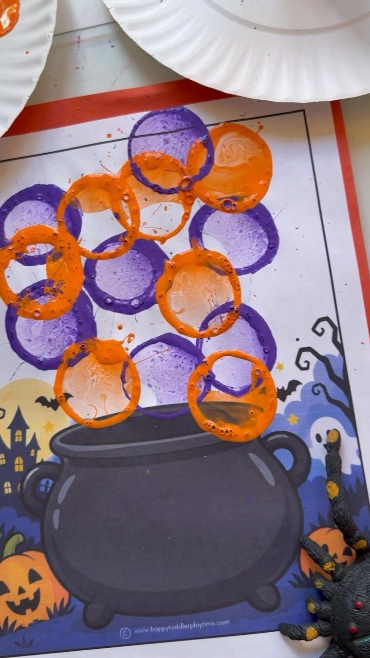 Painted orange and purple bubbles floating above a printed black Halloween cauldron craft.