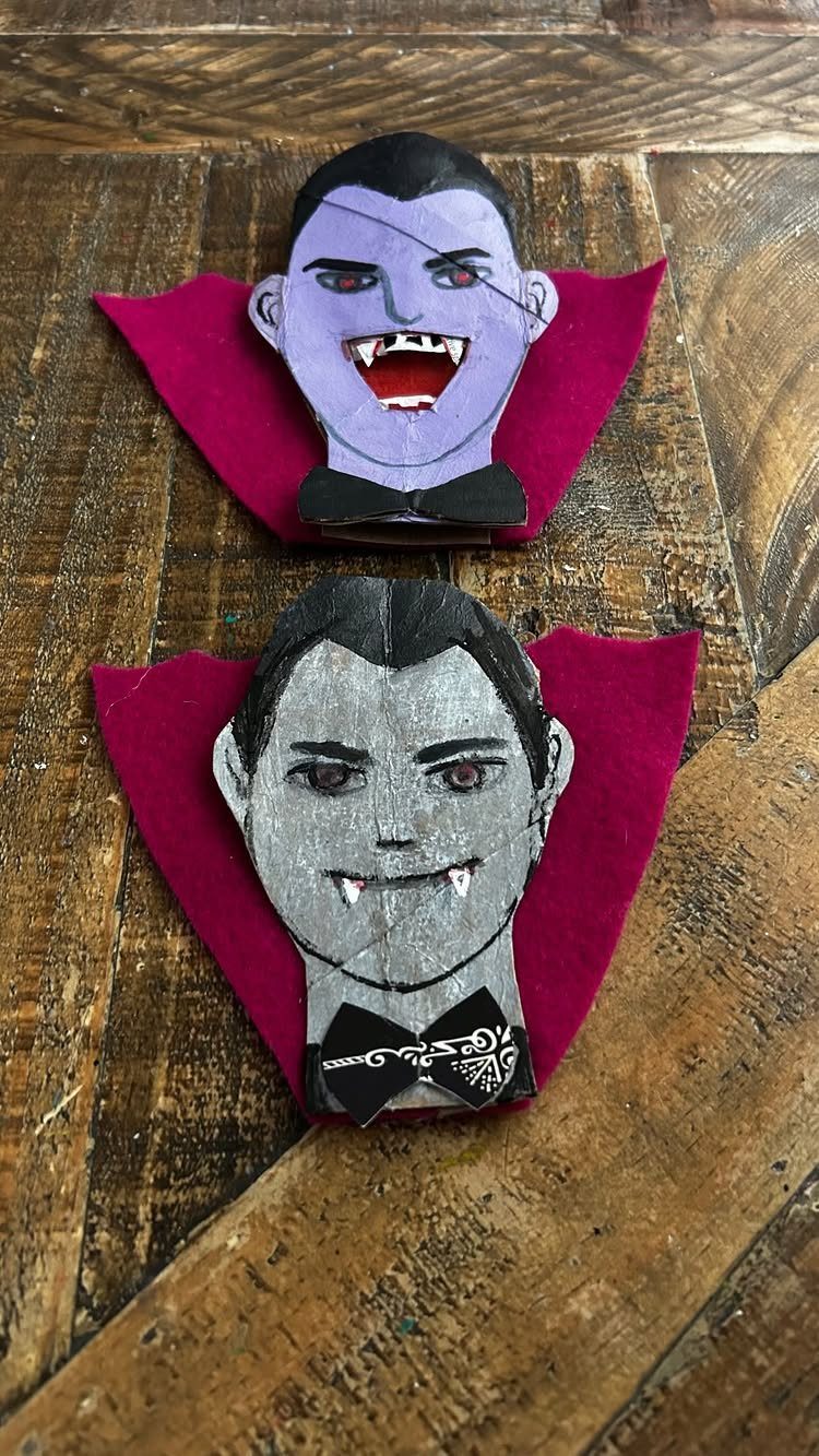 Two cardboard tube vampire crafts with red felt capes on a wooden background