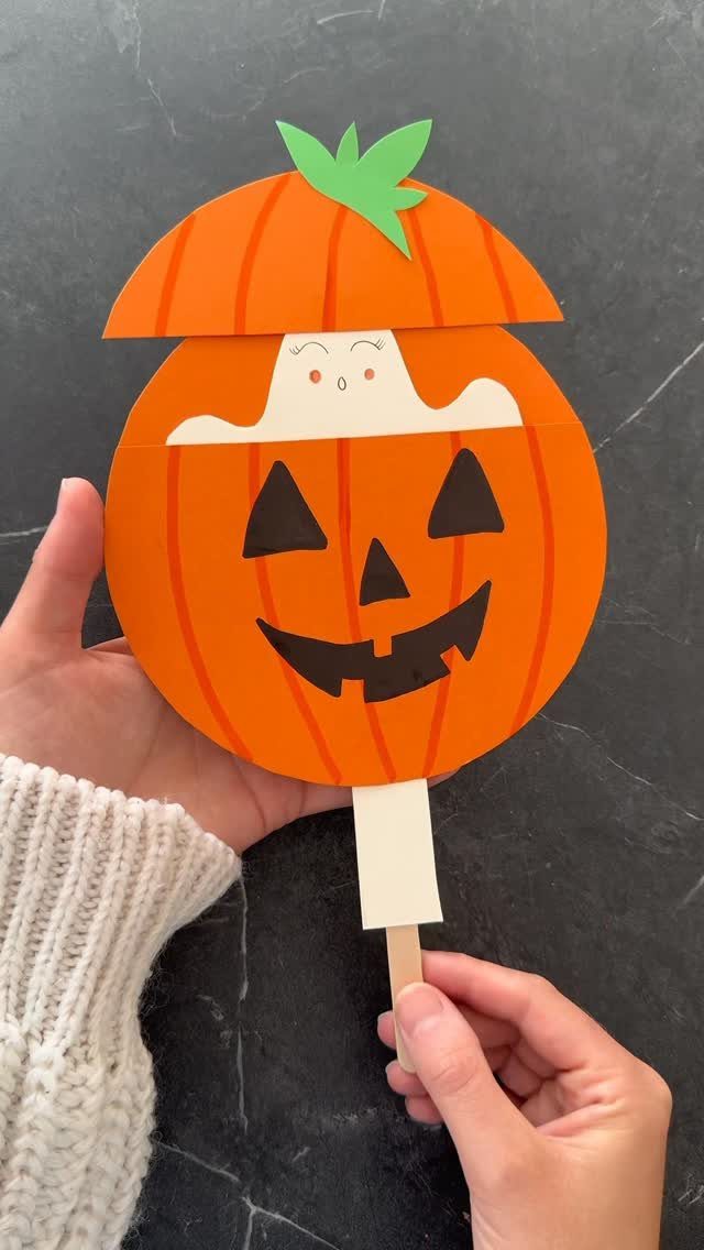 Paper pumpkin craft on a stick with a small ghost peeking out top
