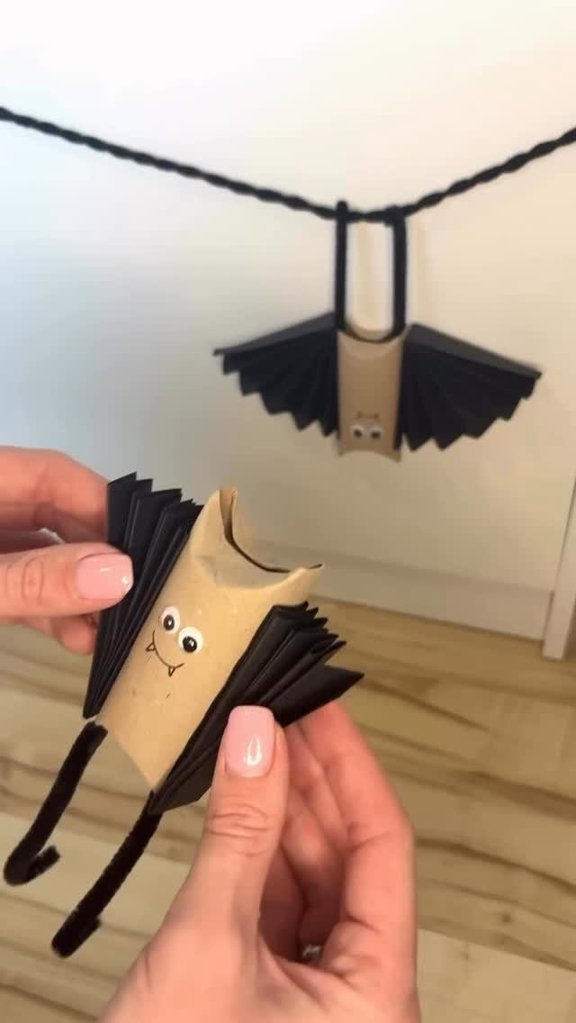 Cardboard toilet paper roll bat craft with black paper wings and googly eyes.