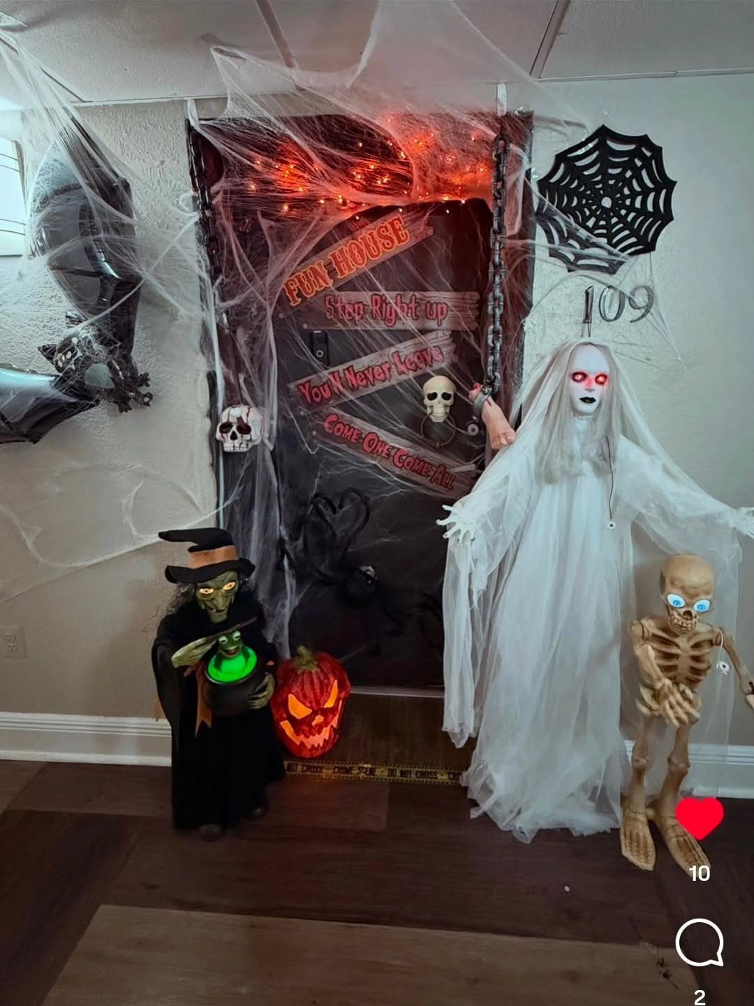 Halloween decorated door with spiderwebs, a ghost, a skeleton, and a witch figure.