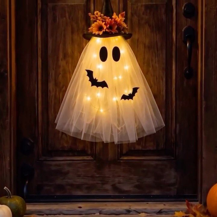 Glowing ghost decoration with a witch hat hanging on a wooden door