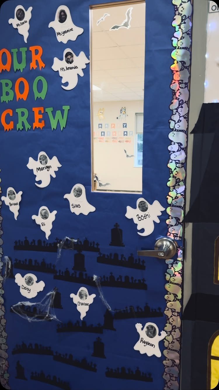 Blue classroom door decorated with ghost cutouts, graveyard silhouettes, and Boo Crew text.