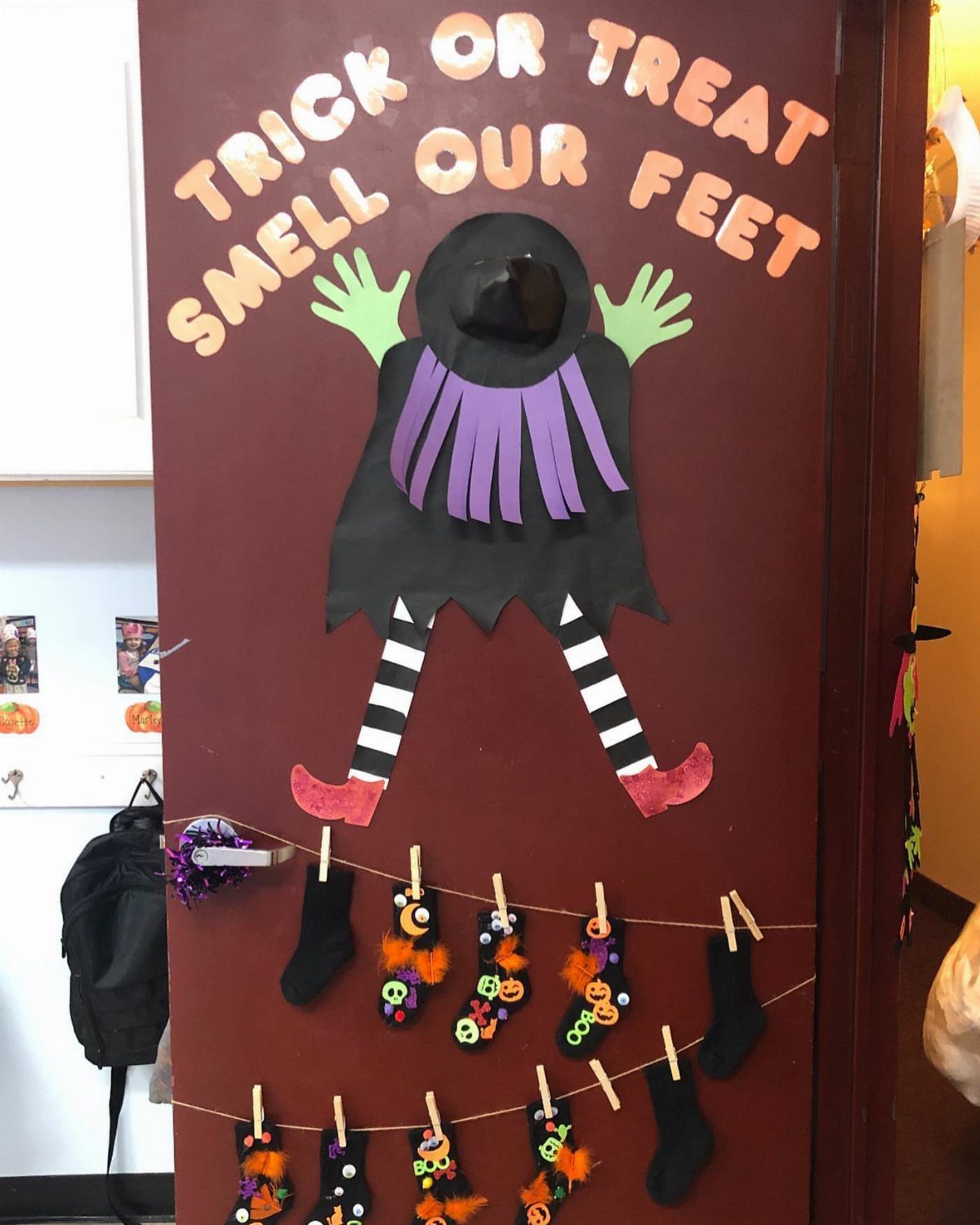 Witch-themed classroom door decoration with orange text and hanging socks on a string