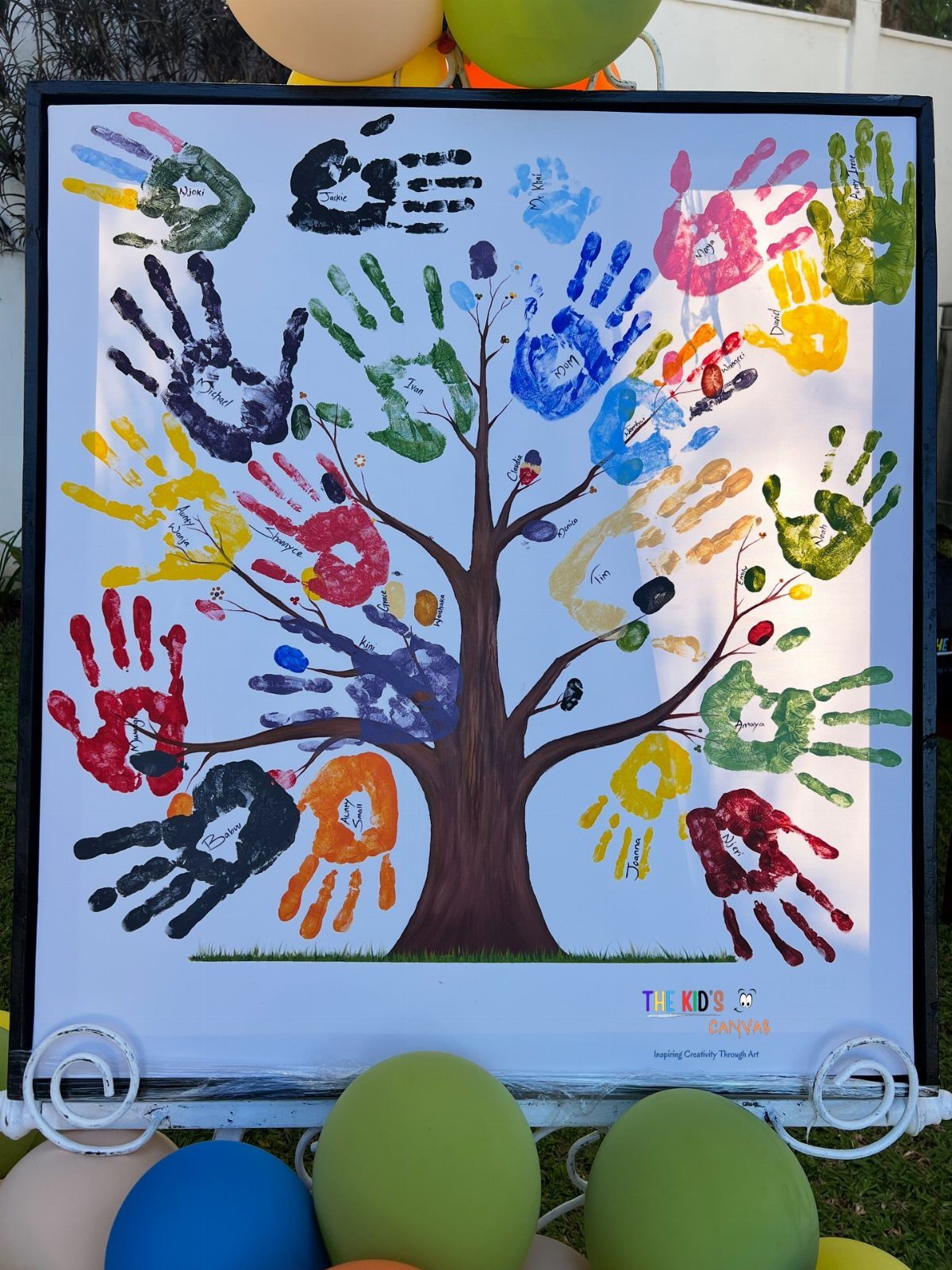 Colorful handprints forming the leaves of a painted family tree in a frame.