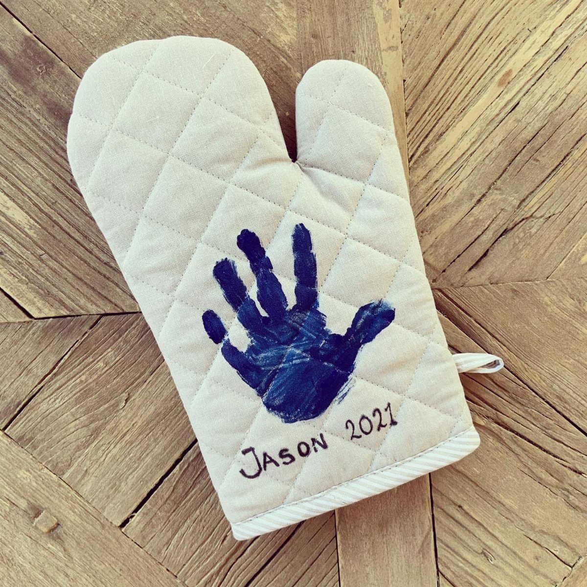 Quilted cream oven mitt with a blue child's handprint and name Jason 2021.
