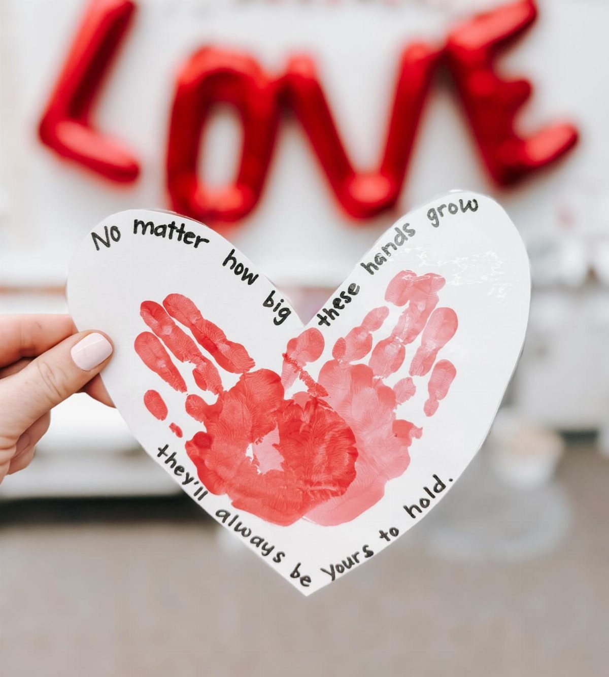 Heart-shaped cutout with red handprints and a sentimental poem about growing hands.