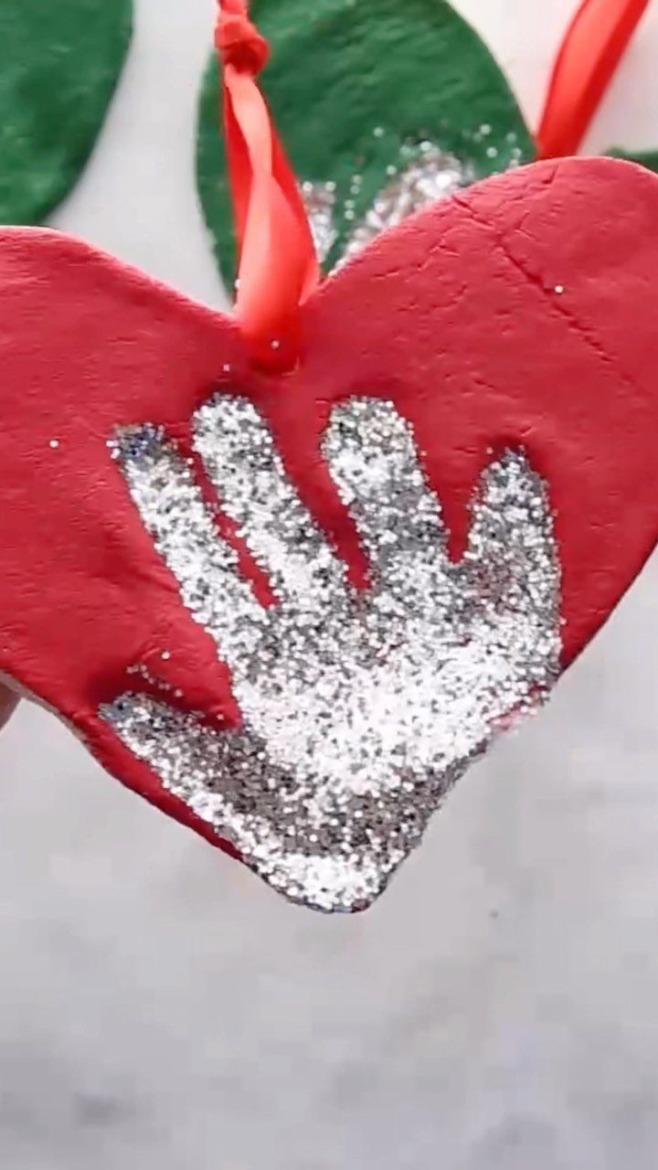 Red heart-shaped salt dough ornament with a silver glittery handprint impression