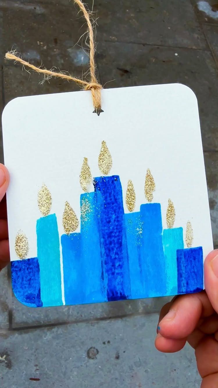 Handmade Hanukkah gift tag featuring a blue painted menorah with gold glitter flames.