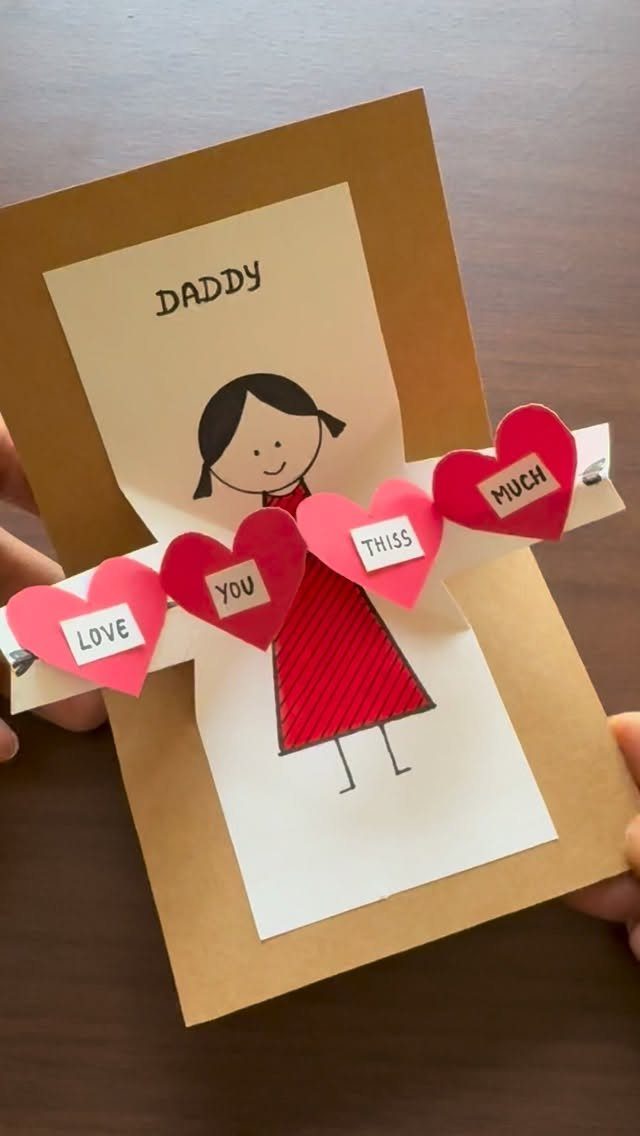 Handmade Father's Day card with a drawing of a girl and red paper hearts.