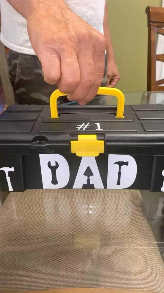 Black plastic toolbox decorated with white DAD text and tool silhouettes.