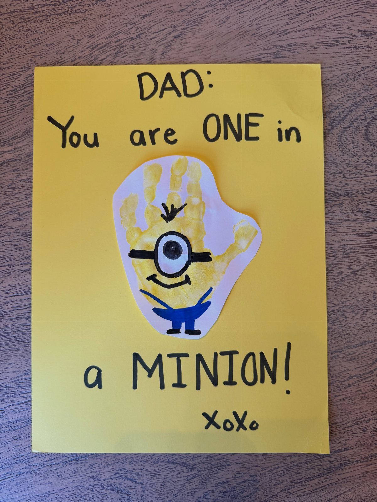 Yellow Father's Day card featuring a Minion character made from a yellow handprint.