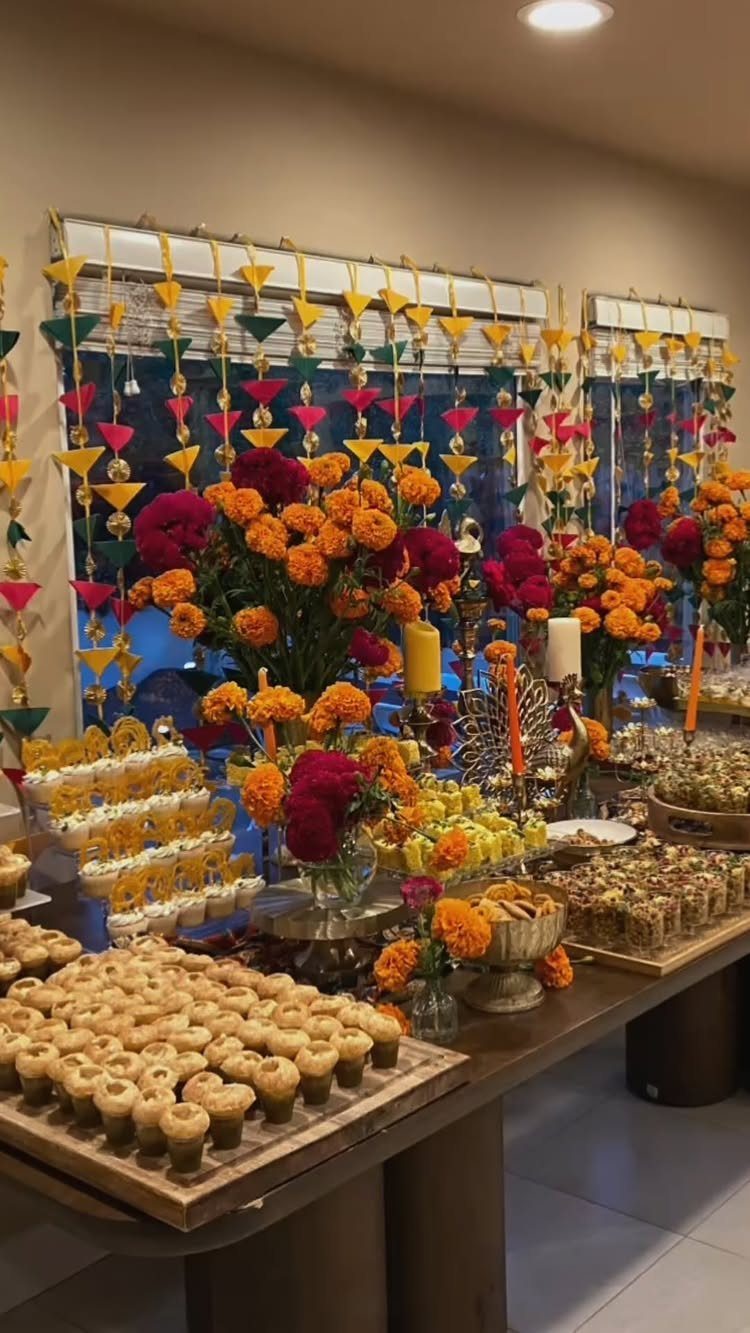 Traditional Indian sweets displayed on a wooden table with marigolds and festive banners.