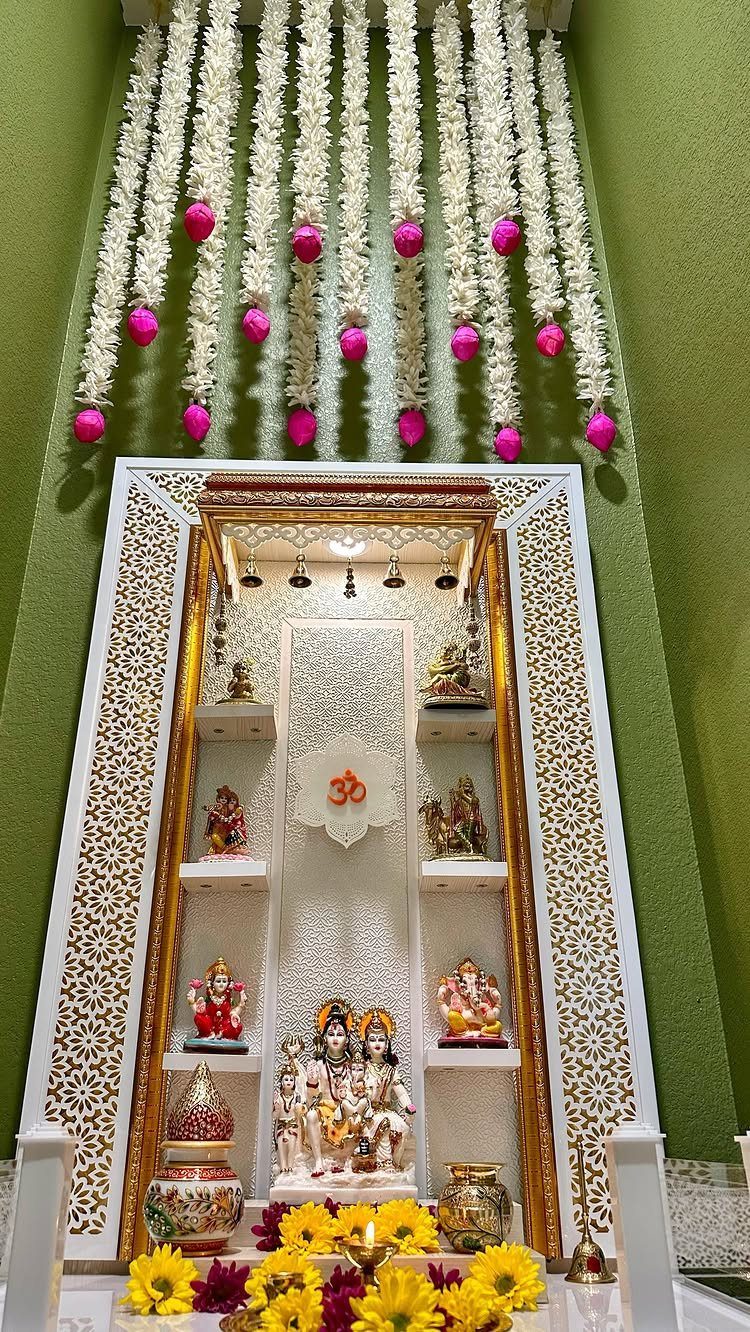 Ornate white and gold puja shrine with deity idols and floral decorations