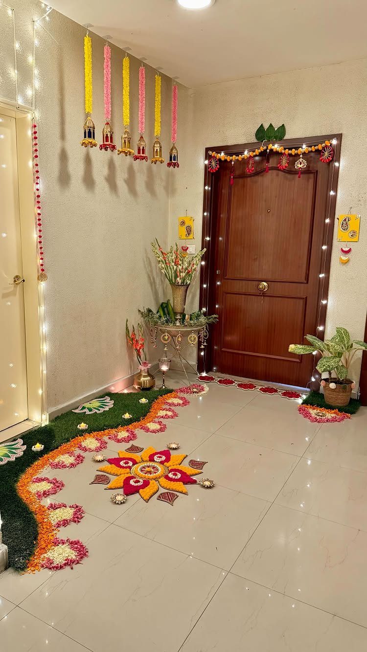 Colorful flower petal rangoli on a tiled floor at a decorated home entrance.