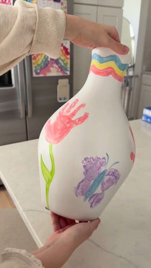 White ceramic vase decorated with a pink handprint and a purple butterfly.