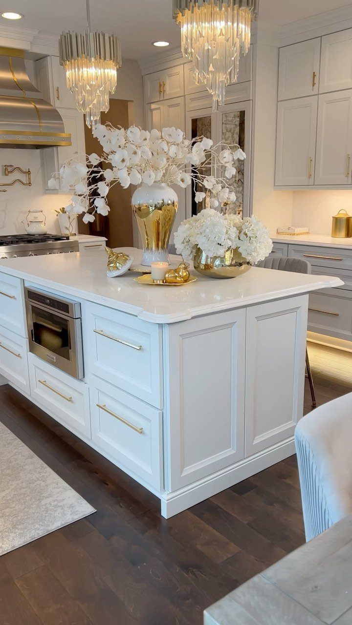 White kitchen island decorated with gold vases and white hydrangea floral arrangements.