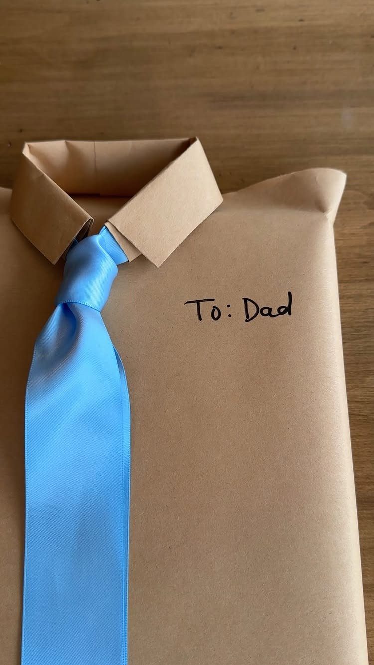 Brown paper package shaped like a shirt with a blue ribbon tie.