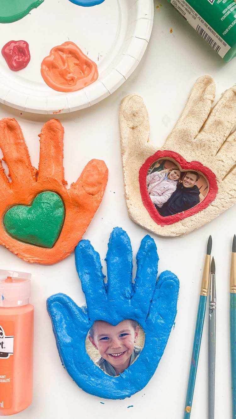 Handprint salt dough frames in orange, blue, and beige with photos and hearts.