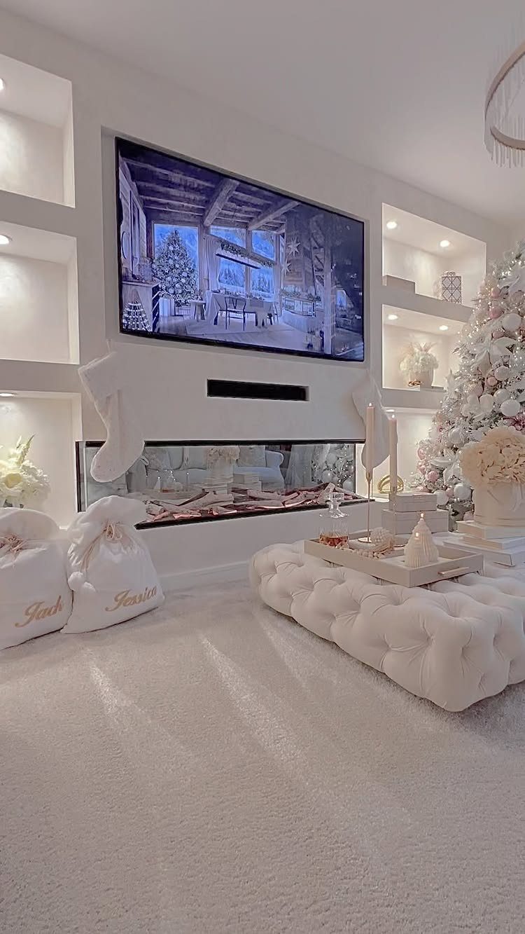 White living room with a Christmas tree, fireplace, and white holiday decorations.