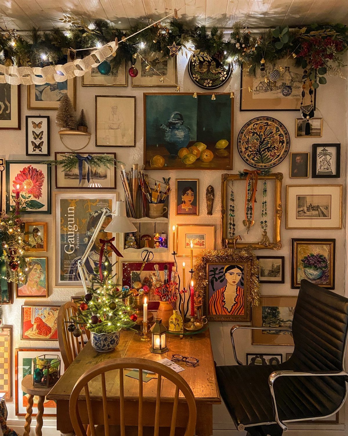 Gallery wall with diverse framed art decorated with a festive Christmas garland and lights