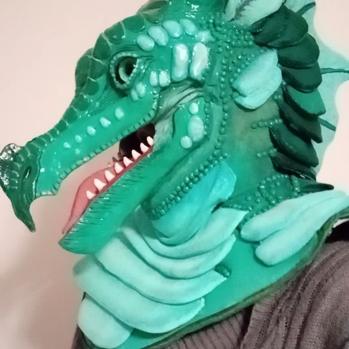 Handmade green dragon mask with textured scales worn by a person.