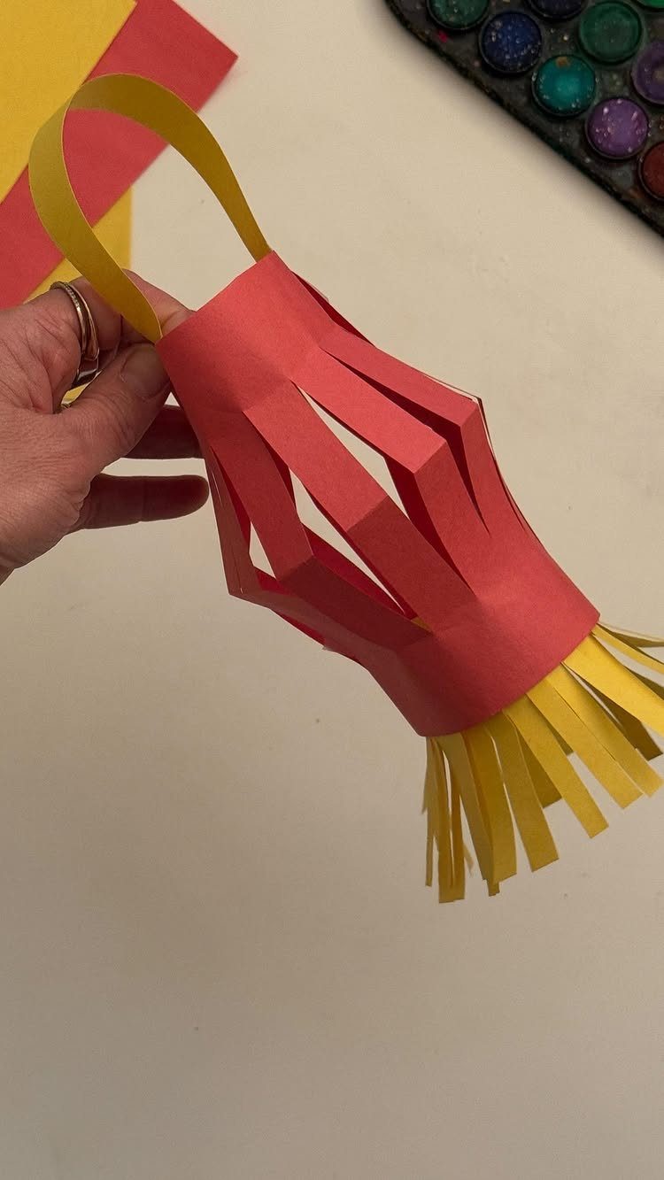 Handmade red paper lantern with yellow accents held against a white background.