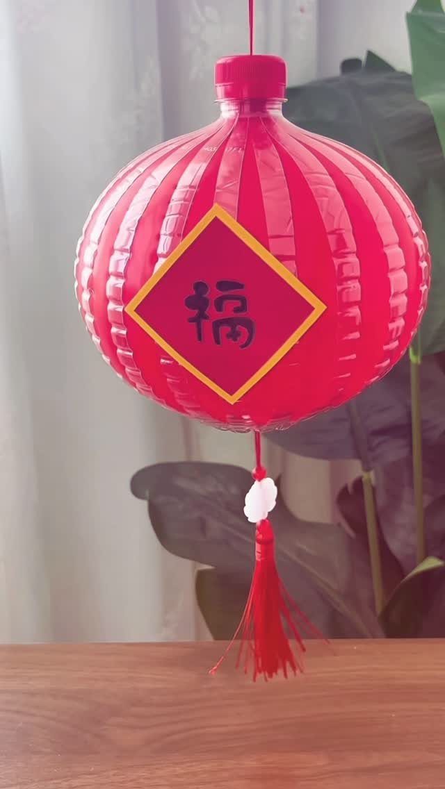 Red plastic bottle lantern with a Chinese character and red tassel hanging indoors.