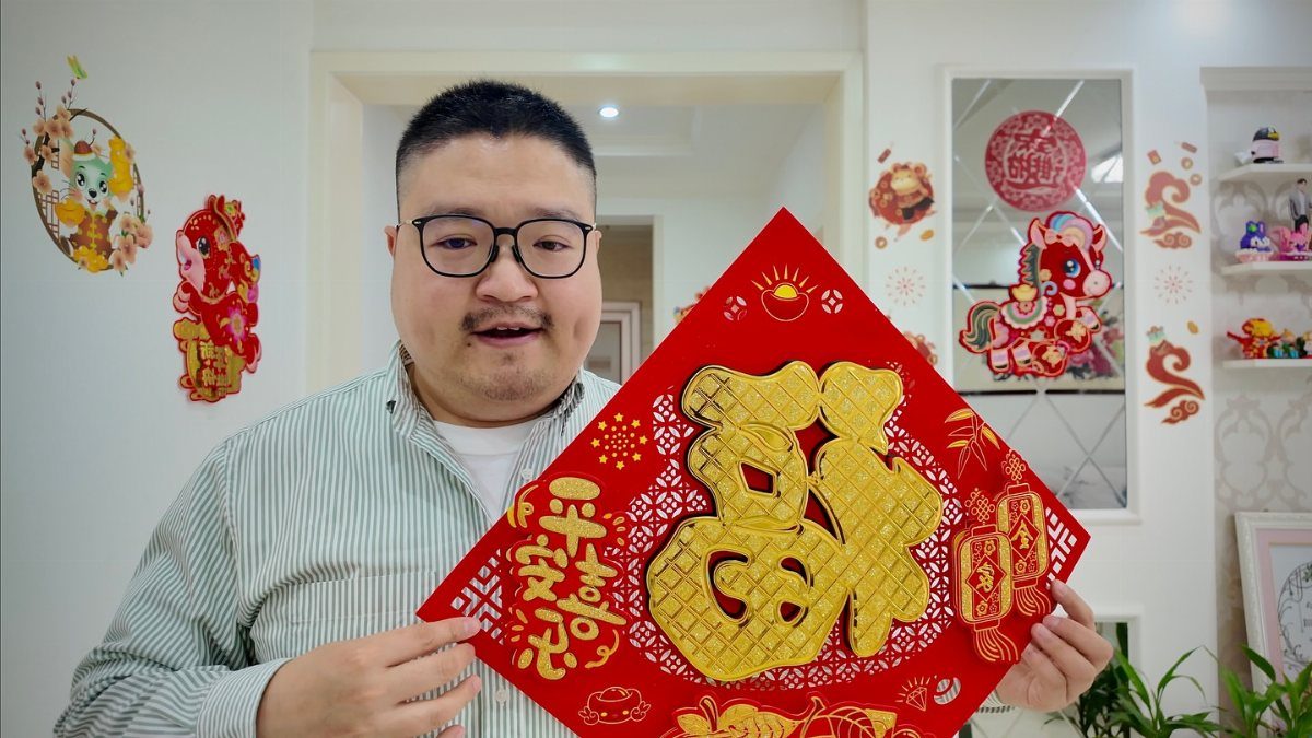 Man holding a red diamond decoration with a large gold Chinese character Fu.