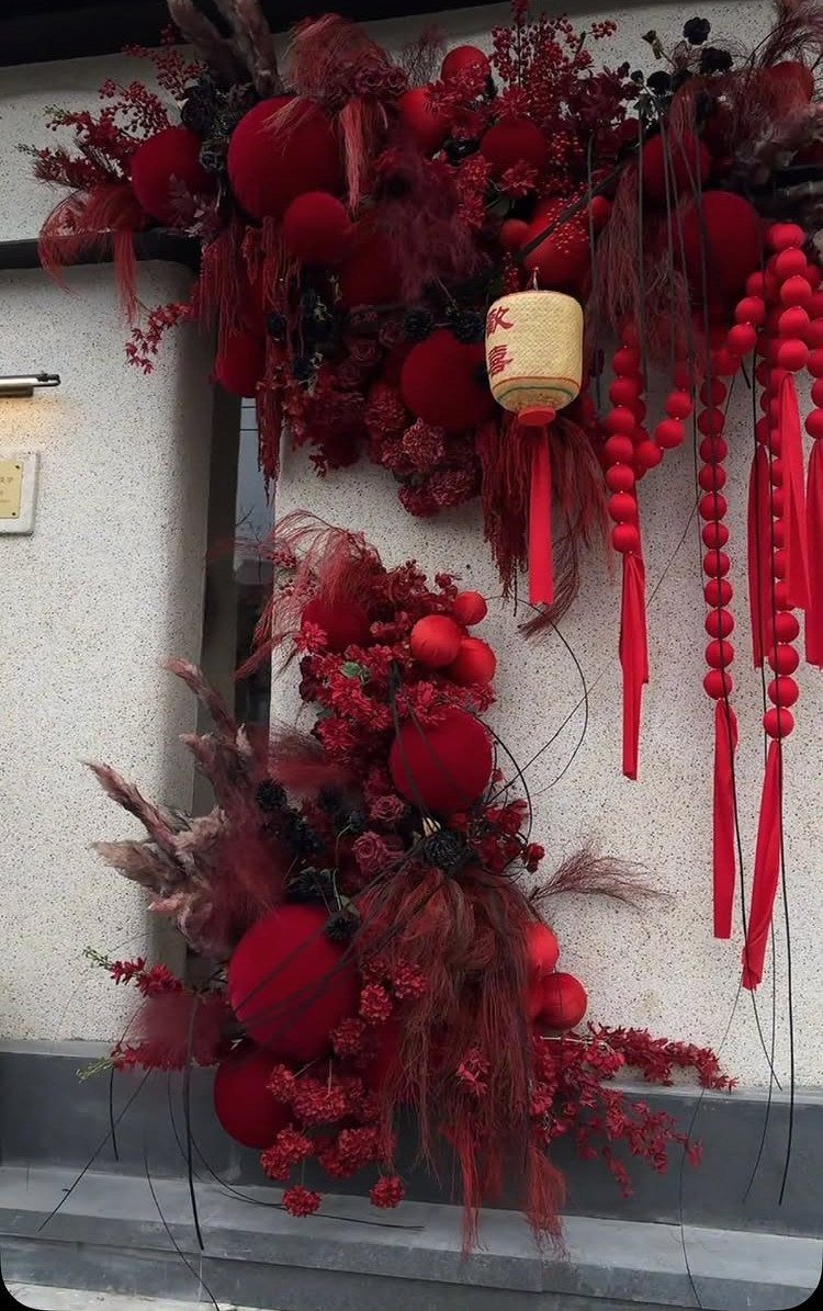 Red floral decorations with lanterns and tassels hanging on a light wall.