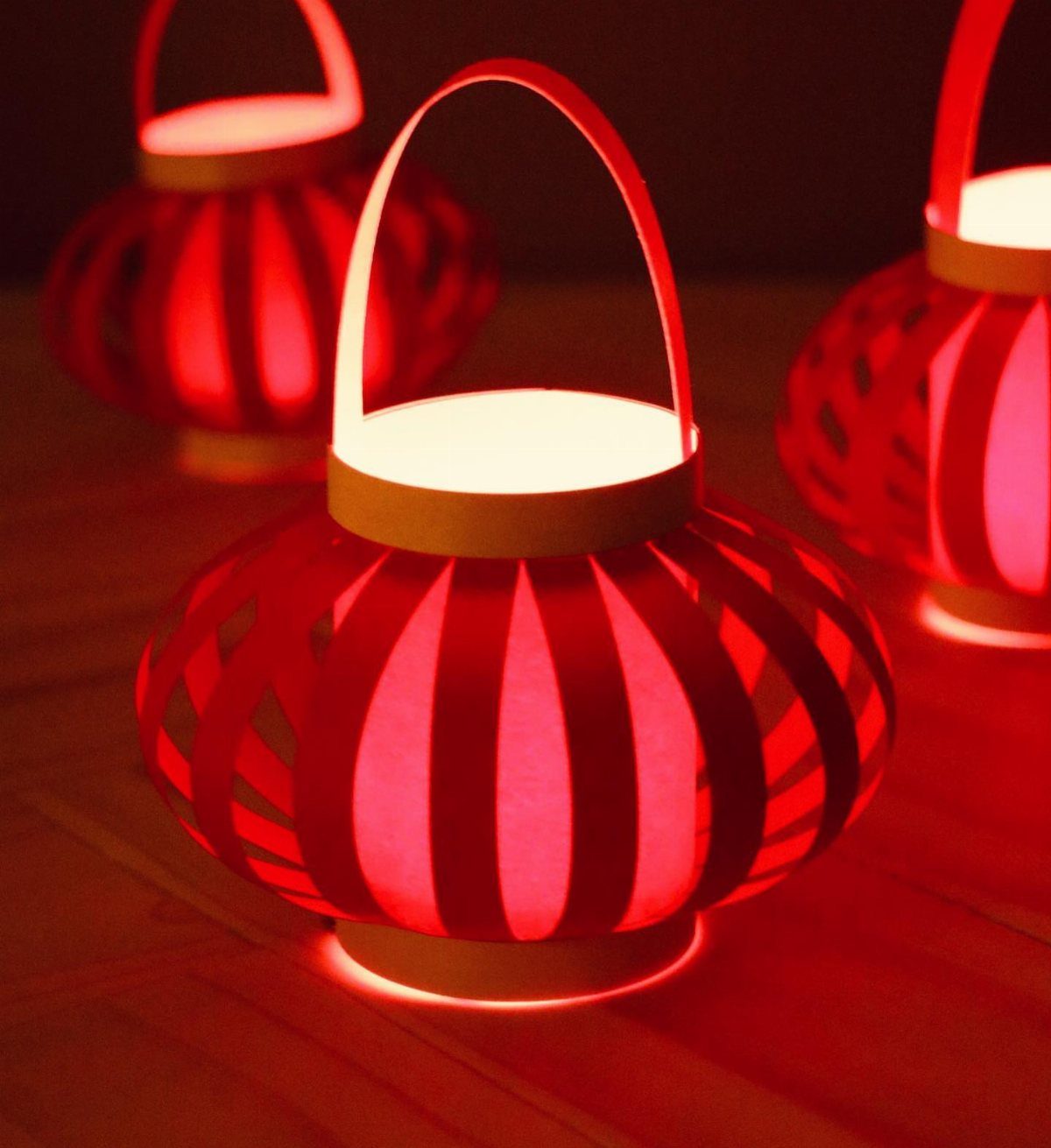Red paper lanterns glowing from within on a wooden surface.