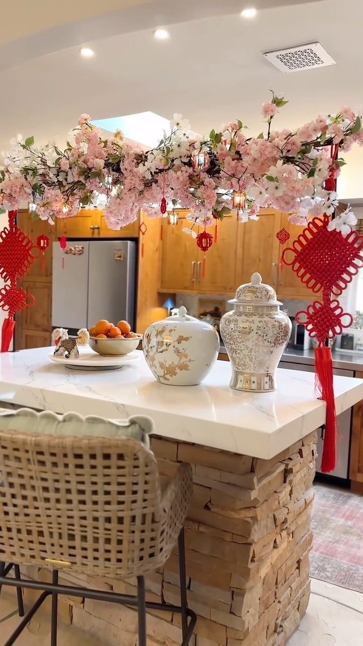 Lunar New Year table decor with pink blossoms, red knots, and oranges on marble.