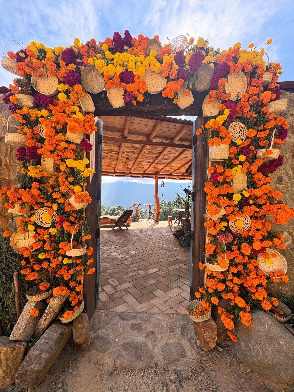Floral archway with orange and purple marigolds and small straw hats framing a porch.