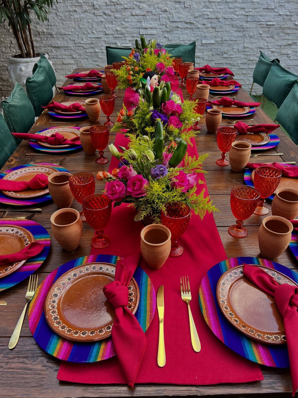 Wooden table set with colorful serape placemats, clay pottery, and floral centerpieces.