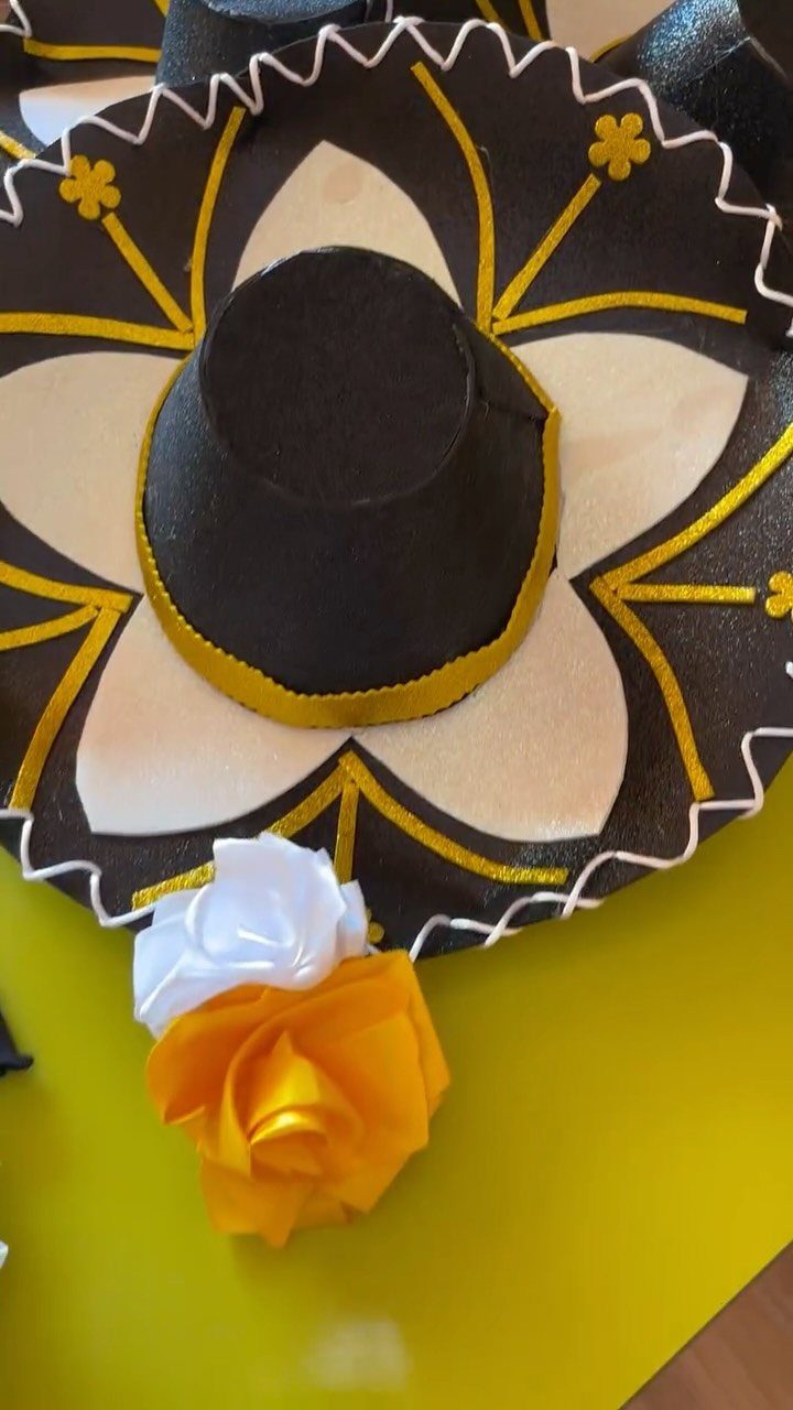 Black sombrero with yellow and white patterns and a yellow fabric rose.