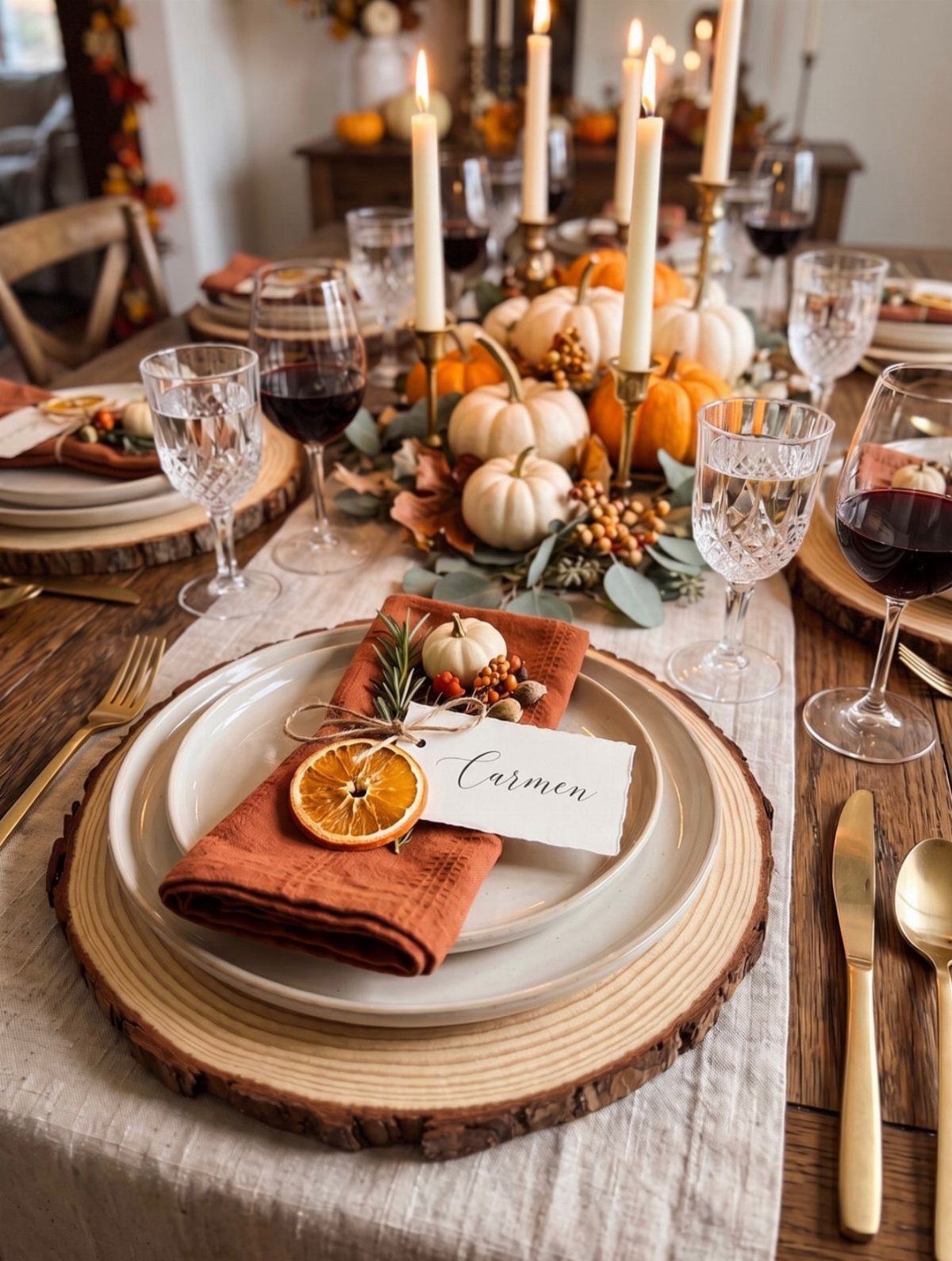 Thanksgiving table setting with white pumpkins, lit taper candles, and rustic wooden chargers.