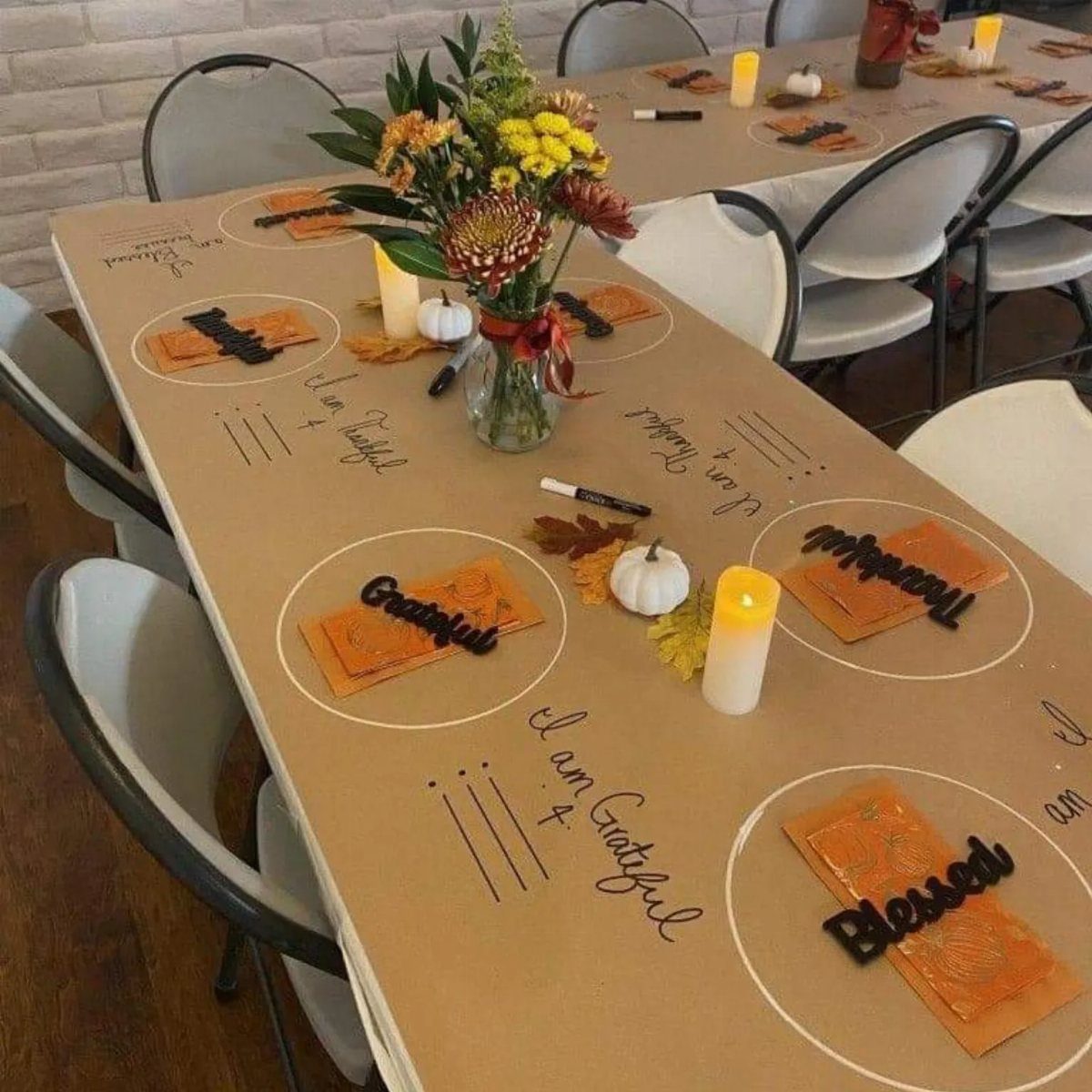 Brown paper table runner with orange napkins, white pumpkins, and floral centerpiece.