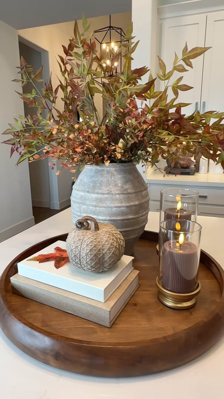 Autumn table arrangement with a wooden tray, ribbed vase, and textured pumpkin.