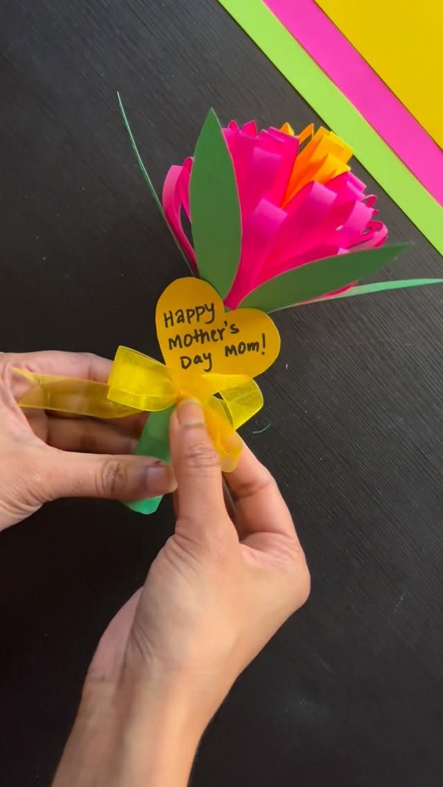 Handmade paper flower with a yellow heart tag and ribbon for Mother's Day.
