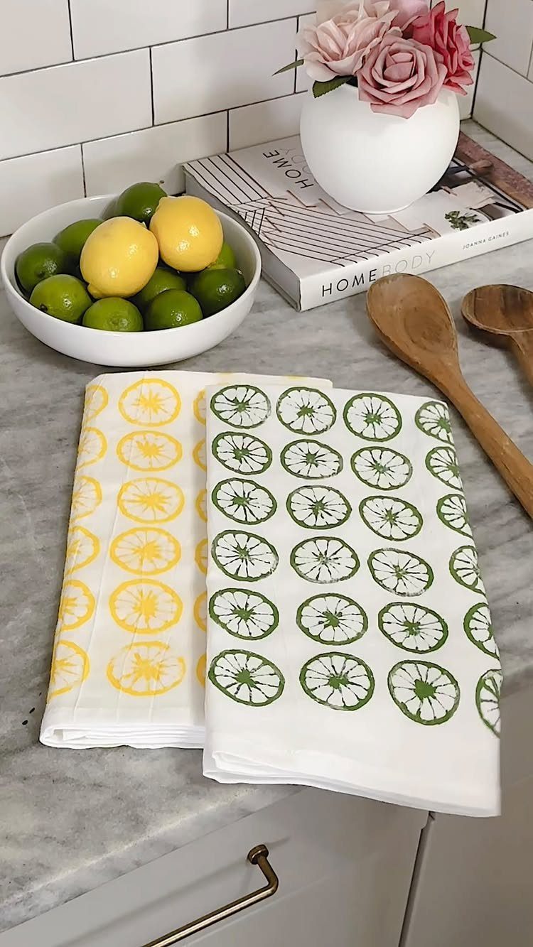 White tea towels with yellow and green citrus stamps on a marble counter.