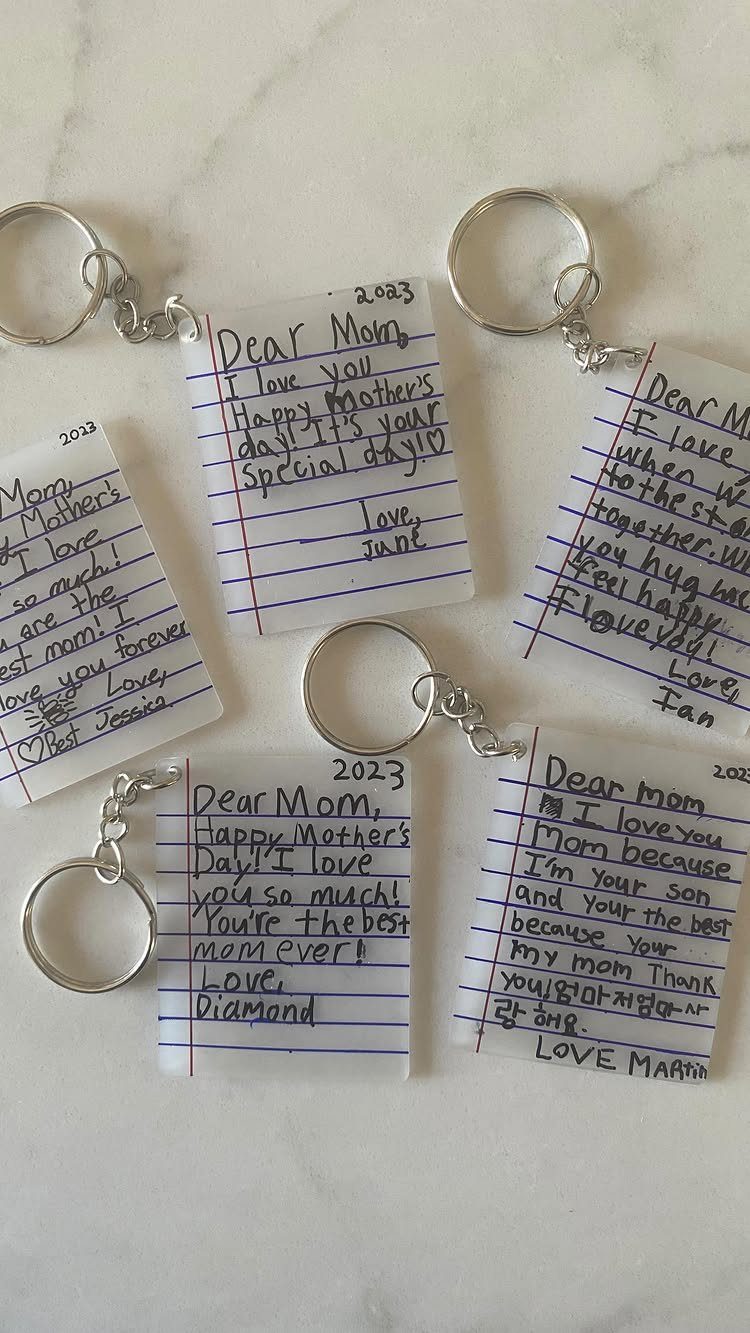 Laminated handwritten notes for Mom attached to silver metal keyrings on marble surface
