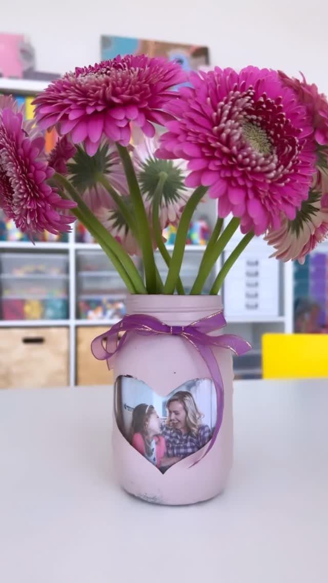 Pink painted mason jar vase with pink daisies and a heart-shaped family photo.