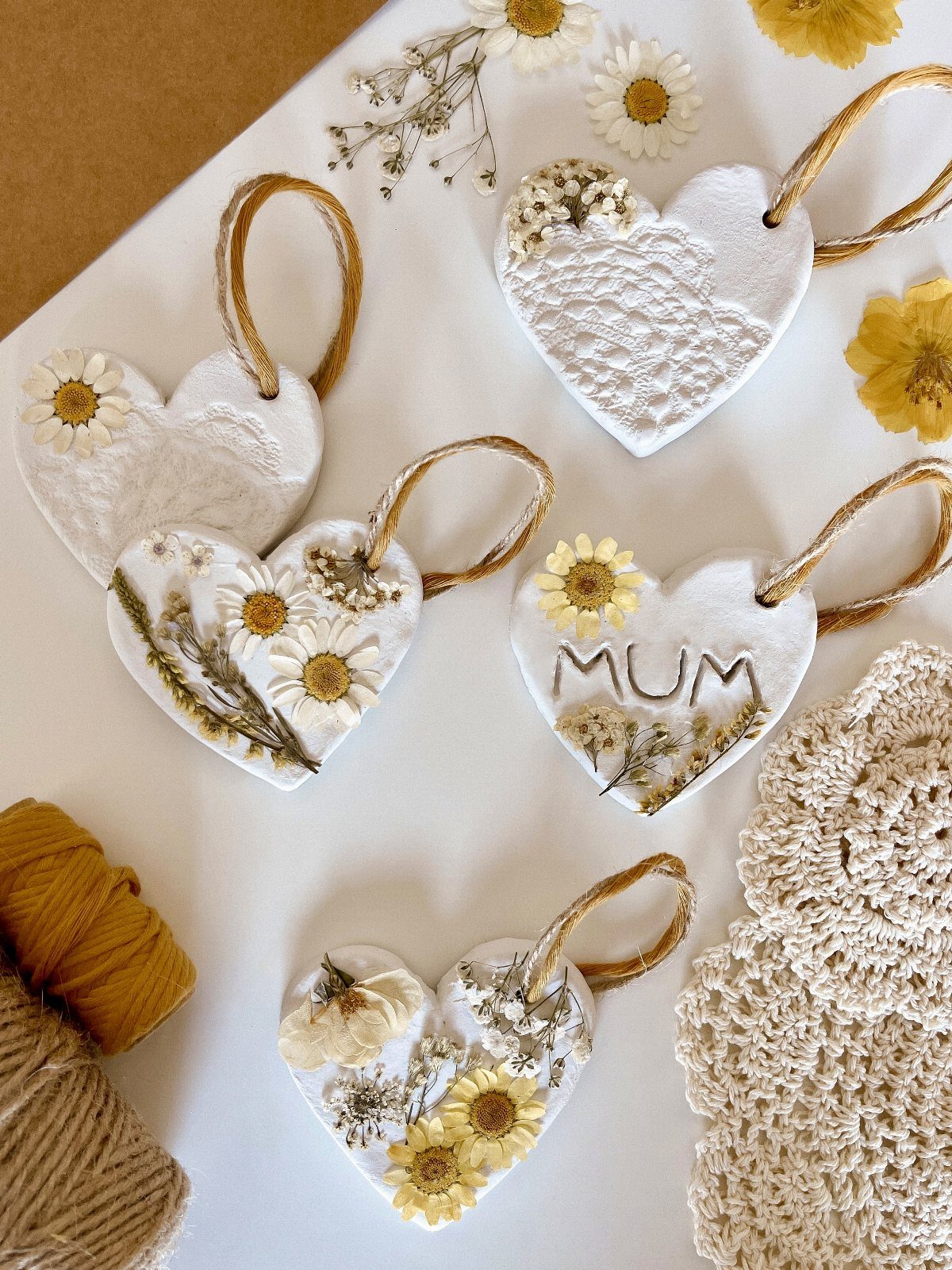White salt dough heart ornaments decorated with pressed yellow flowers and gold string.