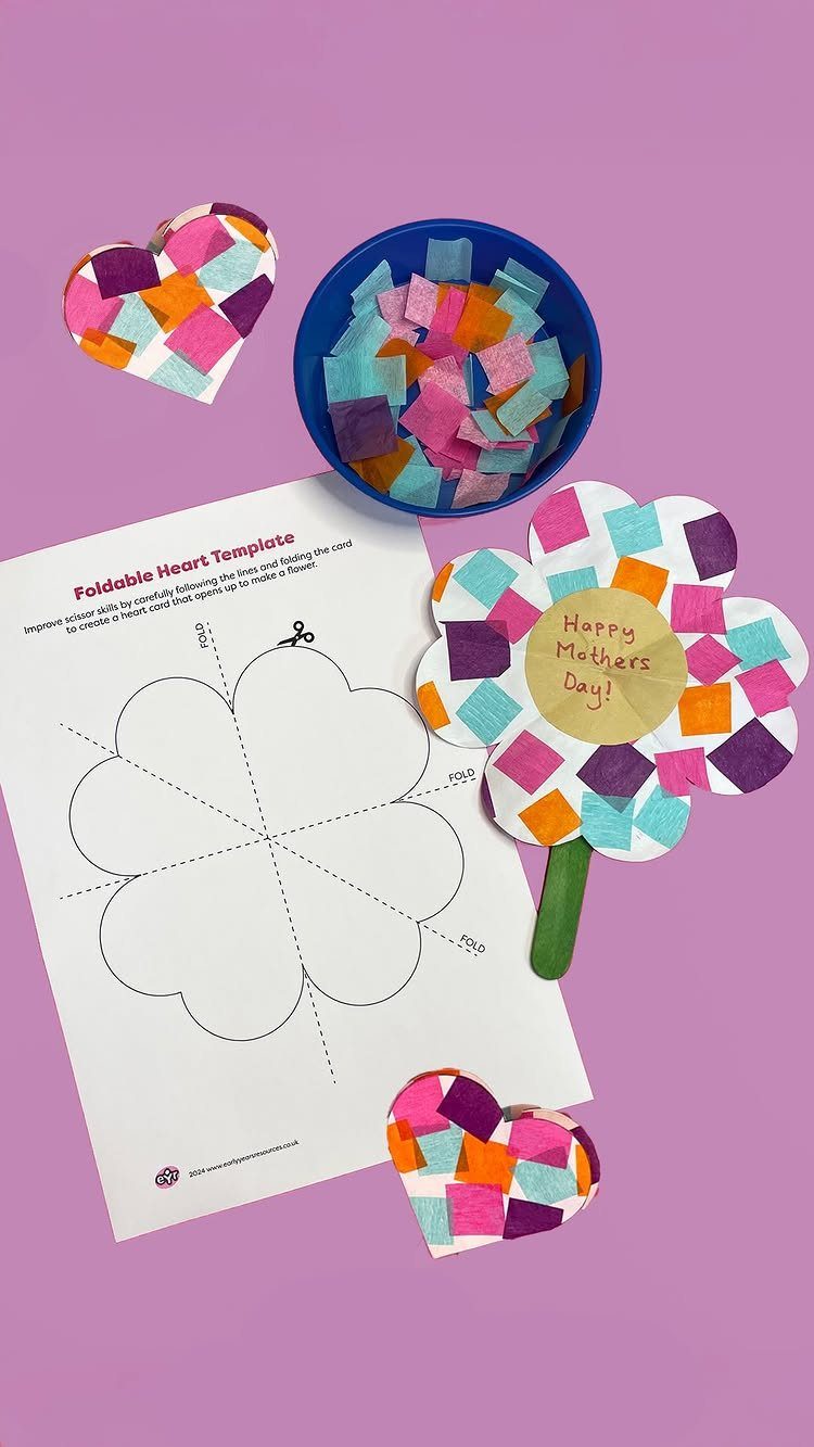 Foldable heart template and colorful paper crafts on a purple surface.