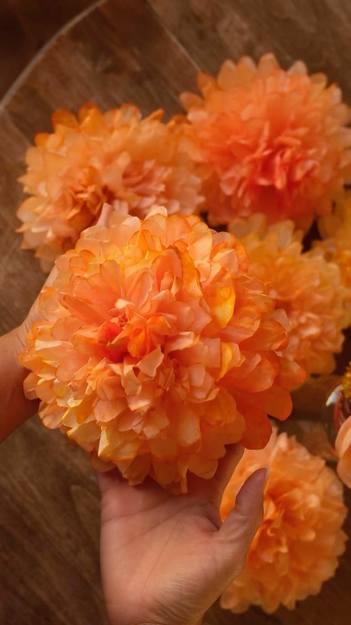 Orange coffee filter flowers held in a hand over a wooden table